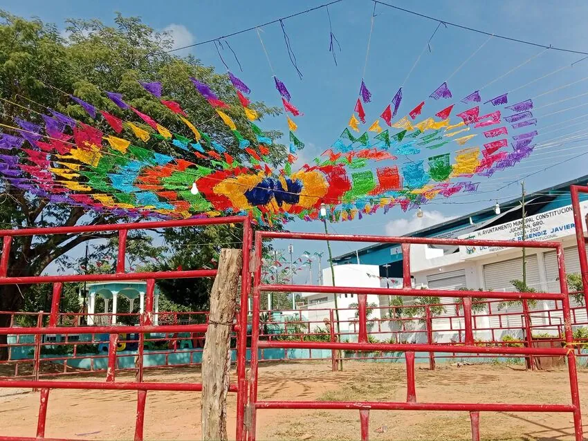 Guirnaldas de papel picado de colores cruzando el cielo del pueblo